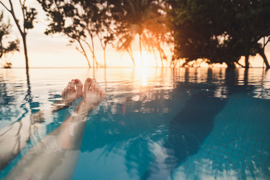 Legs of woman in infinity pool at sunset, Nai Thon Beach, Phuket, Thailand