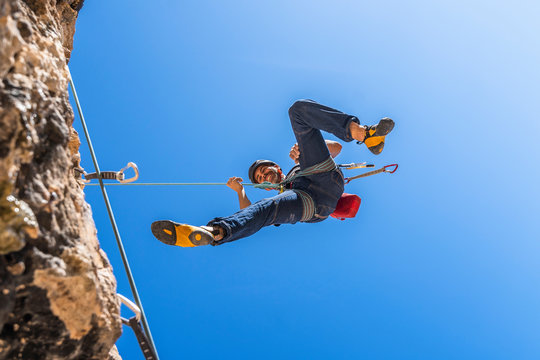 Smiling climber abseiling from rock face