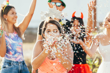 Brazilian Carnival. Young woman in costume enjoying the carnival party blowing confetti