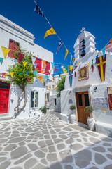 Greek island colorful plaza street with old white architecture buildings and a church in Mykonos, Cyclades, Greece