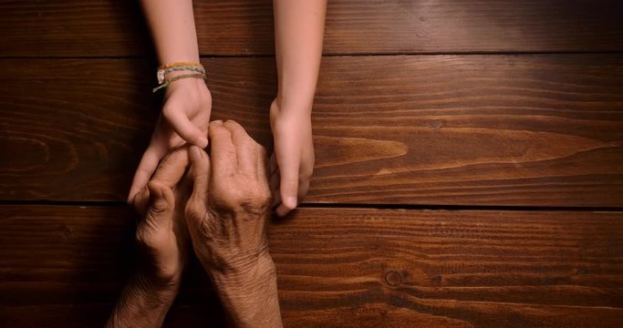 HELPING HAND. Detail of a Child's Hands Holding the Senior Woman Hands