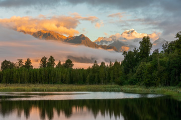 New Zealand, Westland District, Fox Glacier, Lake Matheson at dawn with mountains shrouded in fog in background