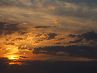 Fototapeta na wymiar Clouds highlighted by orange during sunrise at sea