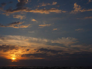 Sunrise in clouds over dark sea