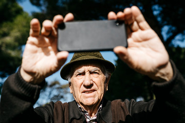 Old man taking pictures with his smartphone