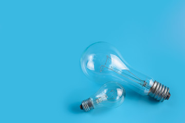 Big huge and normal small classic incandescent lamps on a blue background.