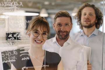 Portrait of confident business team behind a glass pane in office