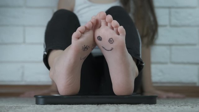 Feet of a child with painted faces. Emoticons on the feet of a child.