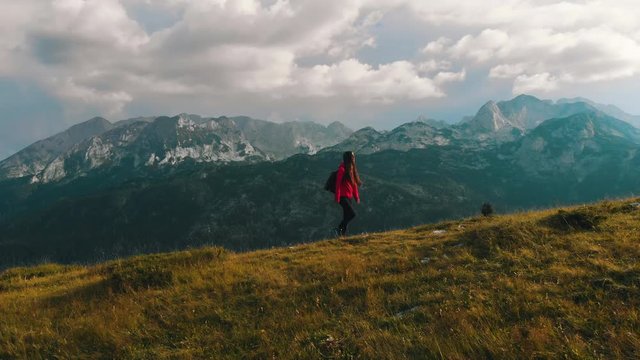 Young female hiker with backpack walking towards sunset. Mountain Durmitor, Montenegro.