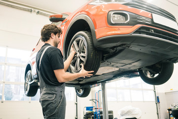 Car mechanic in a workshop changing tire