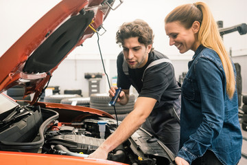 Car mechanic talking to client in workshop