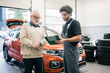 Car mechanic explaining check list to client in workshop