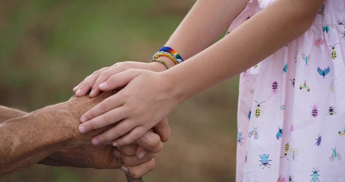 HELPING HAND. Detail of a Child's Hands Holding the Senior Woman Hands