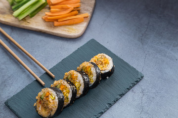 Kimbap rolls with pork and vegetables on a slate plate and chpsticks. Asian cuisine.