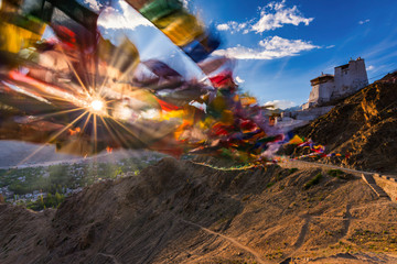 India, Jammu and Kashmir, Leh, Setting sun shining through prayer flags of Namgyal Tsemo Monastery
