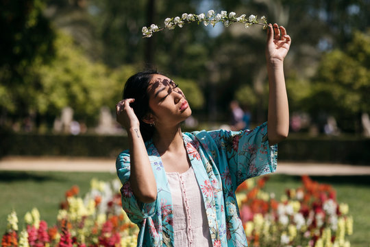 Beautiful young woman holding flower in a public garden in spring