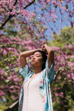 Beautiful young woman with blooming cherry tree in a public garden in spring