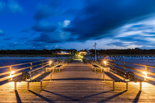 Germany, Mecklenburg-Western Pomerania, Prerow, Clouds over illuminated pier at dusk