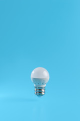 One energy saving small white led light bulb on a blue background. Eco power concept.