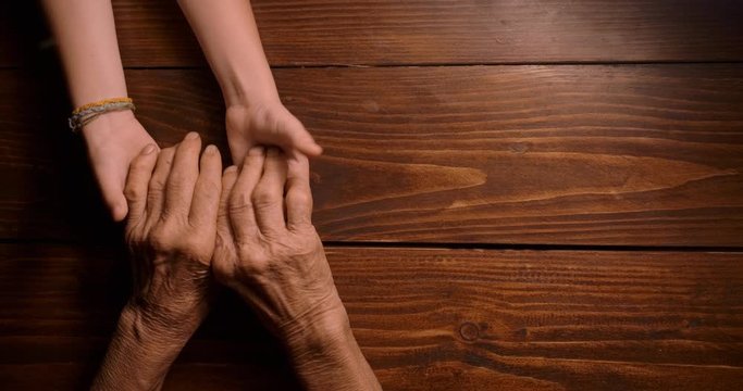 HELPING HAND. Detail of a Child's Hands Holding the Senior Woman Hands