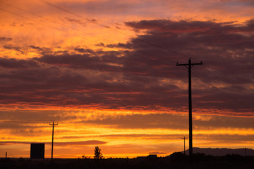Wooden telephone poles/power lines, vibrant sunset