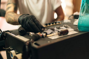 Tattoo artist workplace with machine and bottles with black tattoo ink