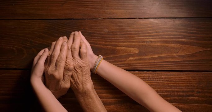 HELPING HAND. Detail of a Child's Hands Holding the Senior Woman Hands