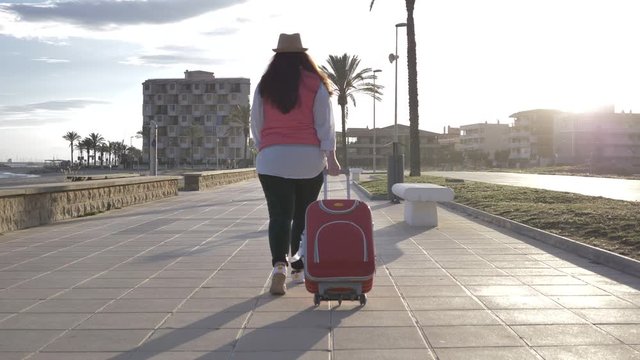 travel woman goes with a suitcase along the promenade
