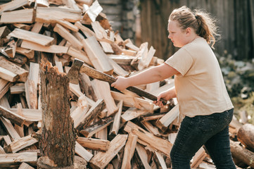 Picture of beautiful chubby girl stands with an axe against the background of a large pile of firewood