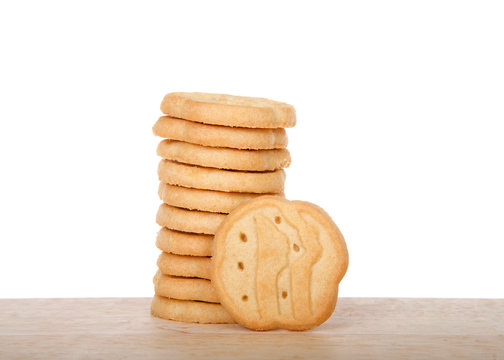 Alameda, CA - April 19, 2019: Stack of Girl Scout cookies, shortbread, also known as trefoils, on a wood table with white background. Available annually during Girl Scout cookie sales.