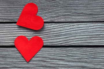 Two red hearts close-up on textured gray wood