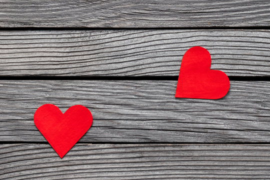 Couple of red paper hearts on gray wood, simple love story, break up