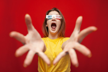 shocked girl in 3D glasses watching a movie and screaming on a red background