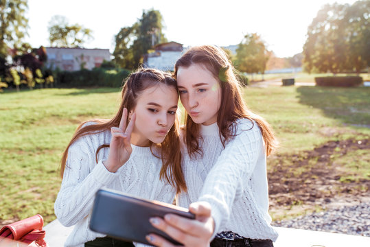 Two girls schoolgirl girlfriends 12-14 years old, taking pictures of themselves on phone, selfie portrait, recording video on social networks, air kiss, online communication in Internet application.