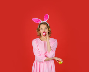 Happy Easter. Blonde girl holds color egg. Spring holiday. Smiling woman in rabbit bunny ears. Woman preparing for Easter. Hunts for Easter eggs. Hunt eggs. Easter celebration concept.