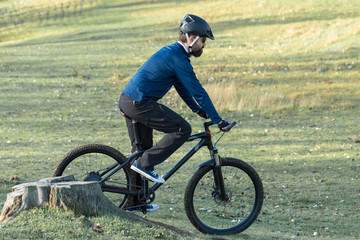 Obraz premium Cyclist in pants and fleece jacket on a modern carbon hardtail bike with an air suspension fork. The guy on the top of the hill rides a bike.