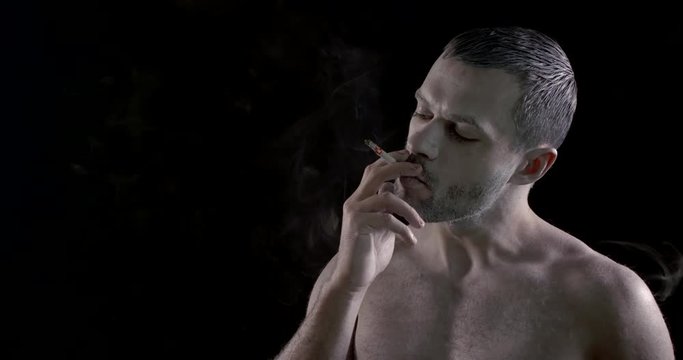 serious man smokes cigarette making rings posing for camera