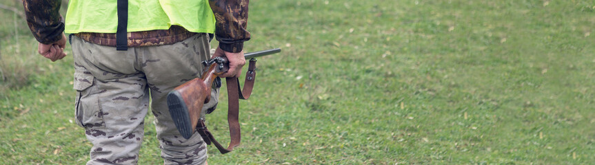 Hunting period, autumn season open. A hunter with a gun in his hands in hunting clothes in the autumn forest in search of a trophy. A man stands with weapons and hunting dogs tracking down the game.