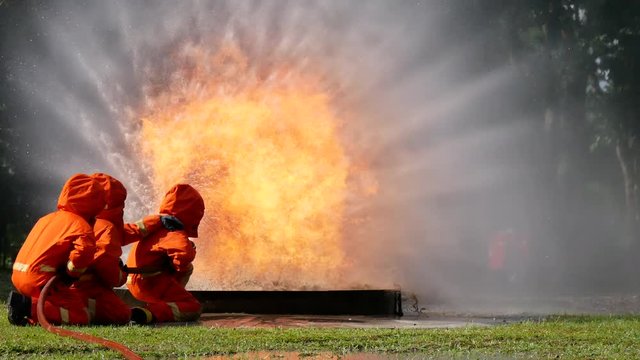 Firefighter fighting with fire flame protection property. Fireman wear hard hat, body safe suit uniform for protection from fire operation. Rescue trained in fire fighting extinguisher hazardous fires
