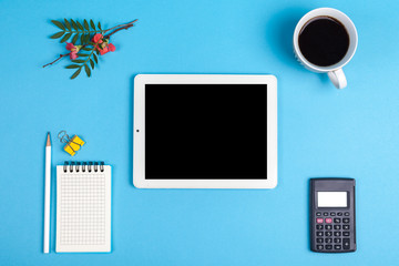 workspace top view. office Desk with office supplies, coffe, calculator and tablet computer. top view blue background