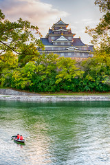 Okayama Crow Castle or Ujo Castle in Okayama City on the Asahi River in Japan. With Little Boat In Foreground.