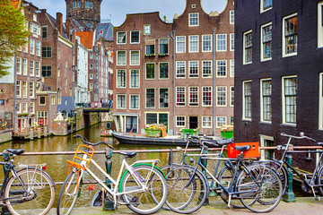 Fototapeta na wymiar Traveling Through the Netherlands. City of Amsterdam. Lots of Bicycles in line Along the Canal of Amsterdam.