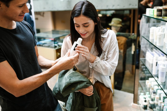 Female Customer Smelling Beauty Product In Store And Smiling