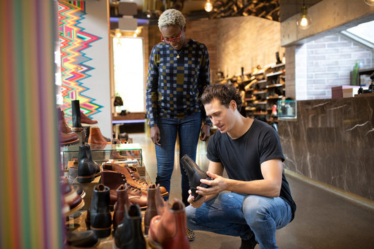 Store Assistant Serving Young Man In Shoe Shop