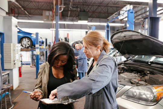 Female Mechanic Asking Customer To Sign Document For Car Service