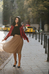 Full-length portrait of enchanting black-haired girl posing with pleased face expression. Outdoor shot of attractive brunette lady in long skirt dancing in autumn day.