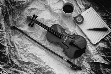 The abstract art design background of Violin and bow put beside red alarm clock and opened book,ongrunge surface background,black and white tone,blurry light around