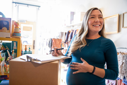 Portrait of cheerful pregnant woman working in baby boutique