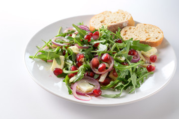 Rocket salad or arugula with pomegranate seeds, red onions and feta cheese served with bread on a...