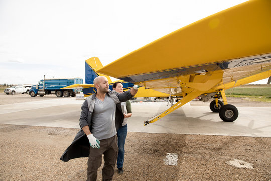 Pilots talking, examining crop sprayer on runway